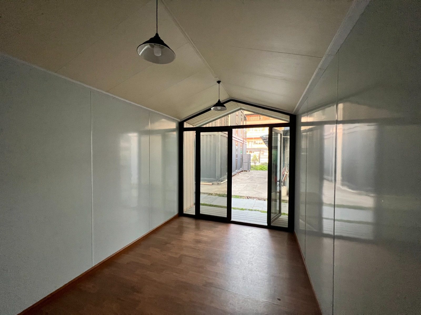 Intérieur d'un module vide : parquet, plafond en pente, grande baie vitrée